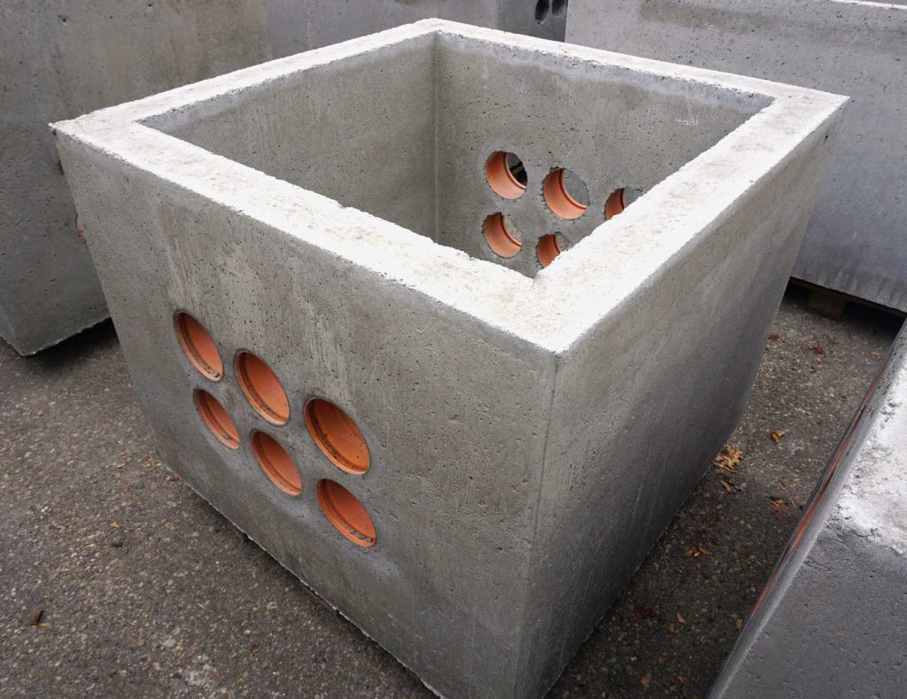 Beton Kabelaufbauschacht mit runden Öffnungen an den Seiten, quadratisch geformt.