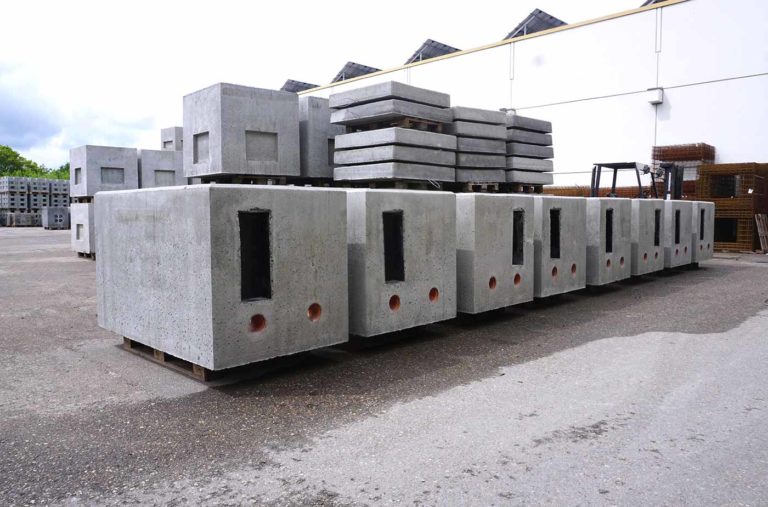 Reihe von grauen Betonboxen auf Holzpaletten in einem Lagerbereich.