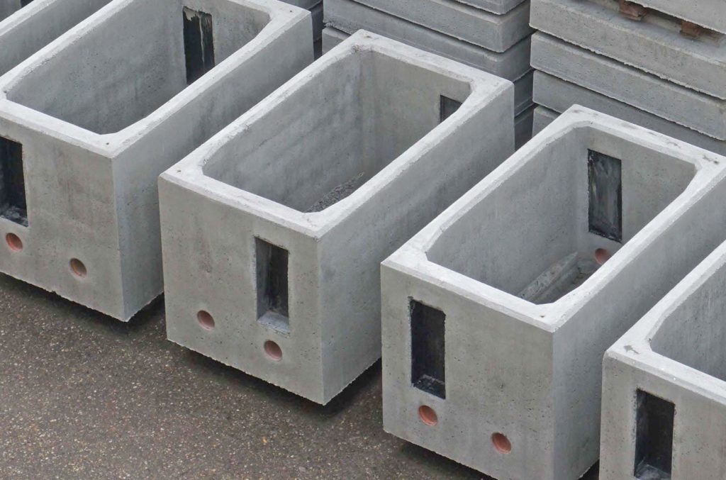 Reihe von rechteckigen Betonboxen für die Glasfaserverteilung in einer Produktionsumgebung.