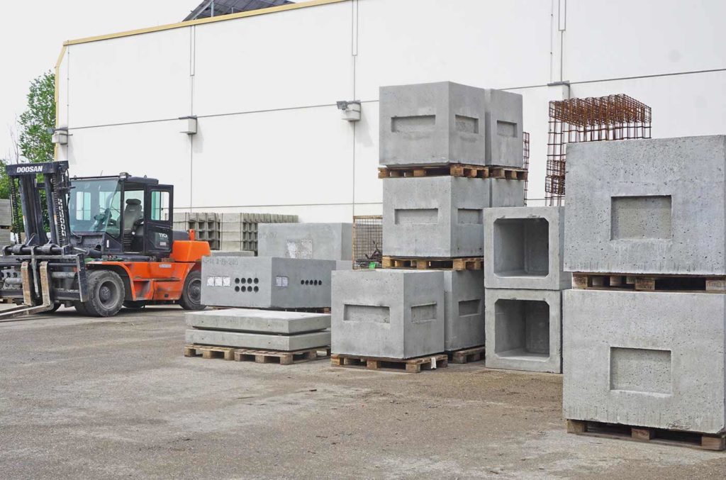 Verschiedene Betonbausteine auf Paletten in einem Lagerbereich.