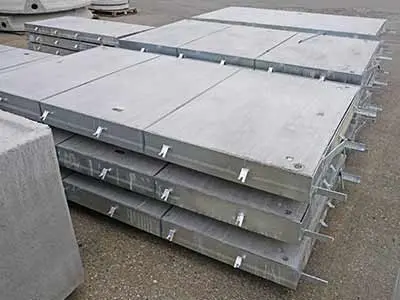 Gestapelte Betonplatten mit integrierten Befestigungselementen auf einer Baustelle.