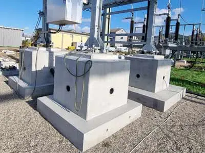 Drei Betonfundamente für elektrische Umspannwerke auf einem Gelände.