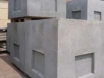 Gestapelte graue Betonblöcke auf einer Holzpalette in einem Lagerbereich.