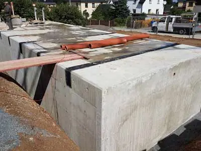 Beton-Löschwasserbehälter mit Rohren und Holzlatten auf der Oberseite.