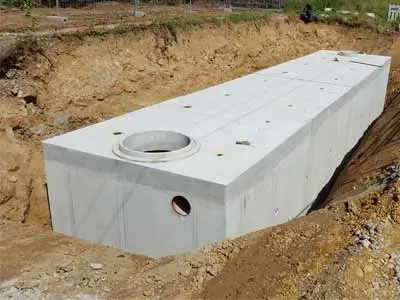Beton Regenrückhaltebecken, das in einem Erdloch installiert ist, mit einem runden Zugangselement.