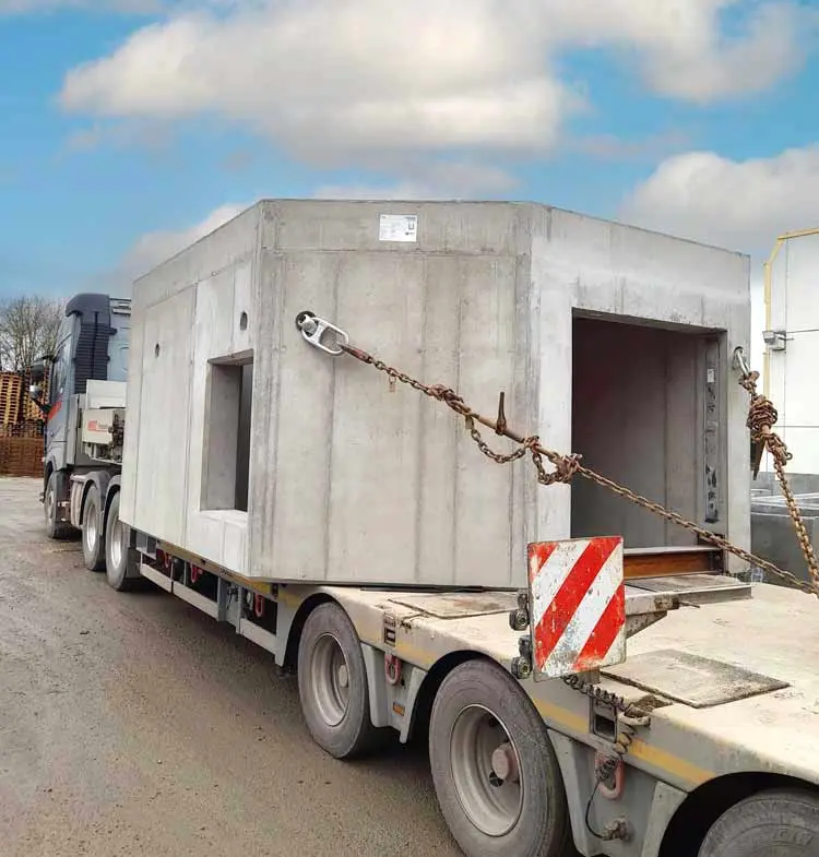 Monolithischer Absenkschacht aus Beton auf einem Lkw mit Anhänger, bereit für den Transport.