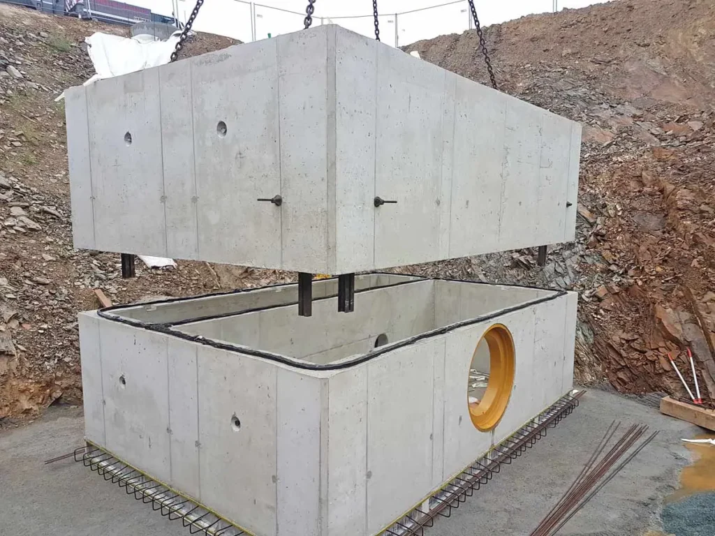 Zwei Betonmodule werden beim Aufbau eines Drosselschachts angehoben und positioniert.