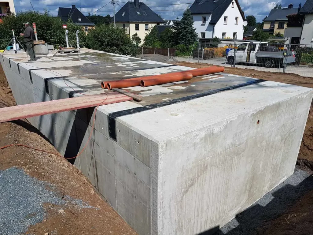 Beton Löschwasserbehälter mit Rohren auf der Oberfläche in einer Baustelle.