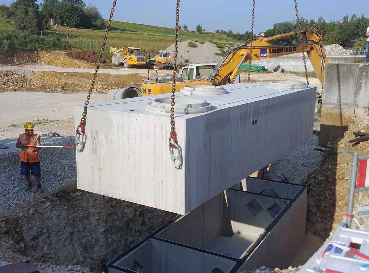 Ein Betonlöschwasserbehälter wird mit einem Kran in eine Grube gehoben.