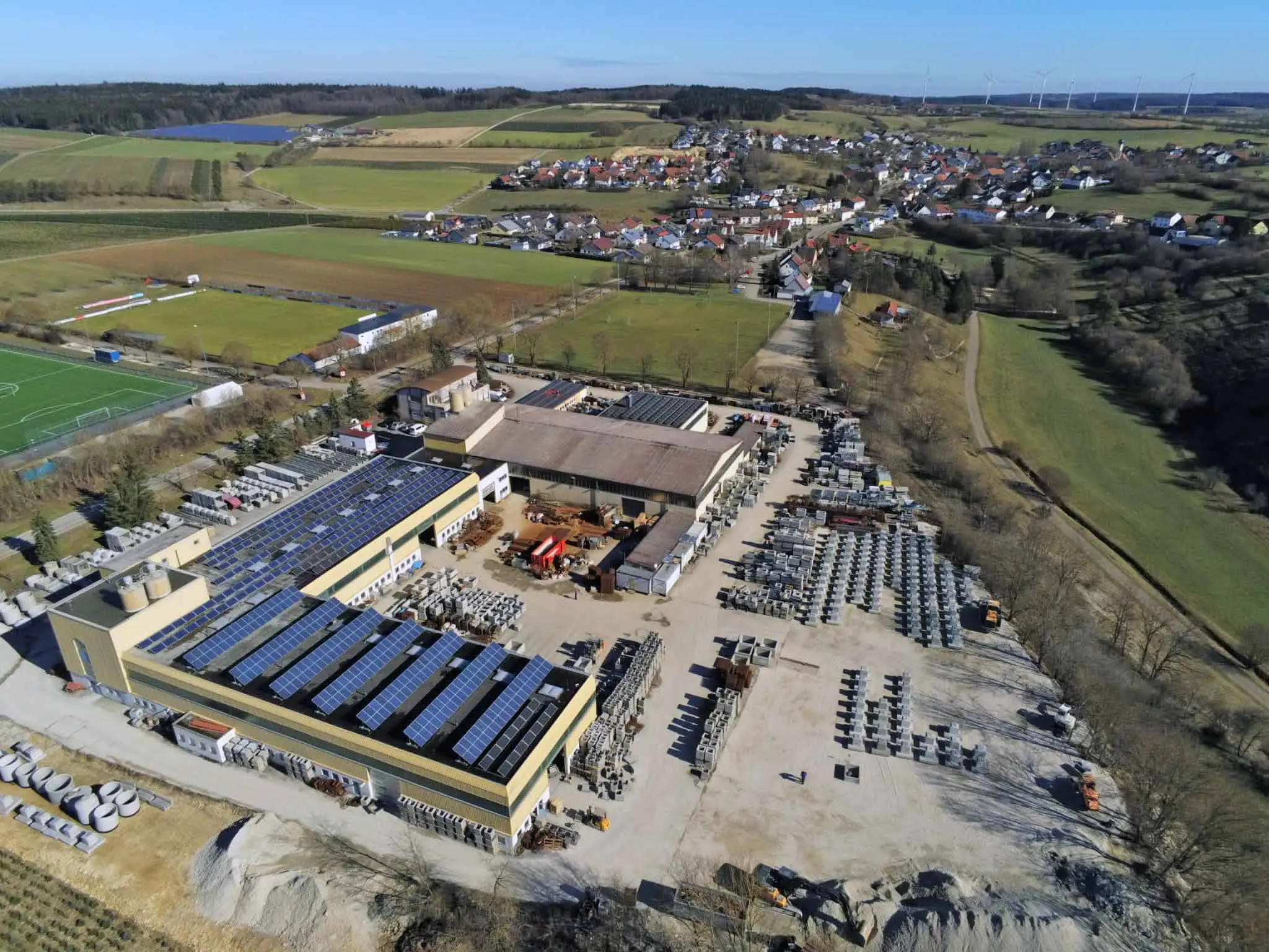 Luftaufnahme eines Industriegebiets mit Gebäuden und Solarpanelen auf dem Dach.