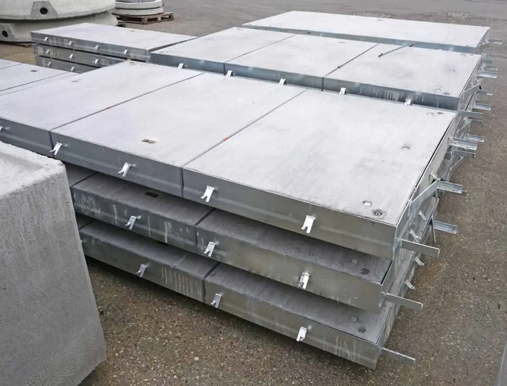 Stapeln von Beton-Schachtabdeckungen mit Metallgriffen auf einer Oberfläche.