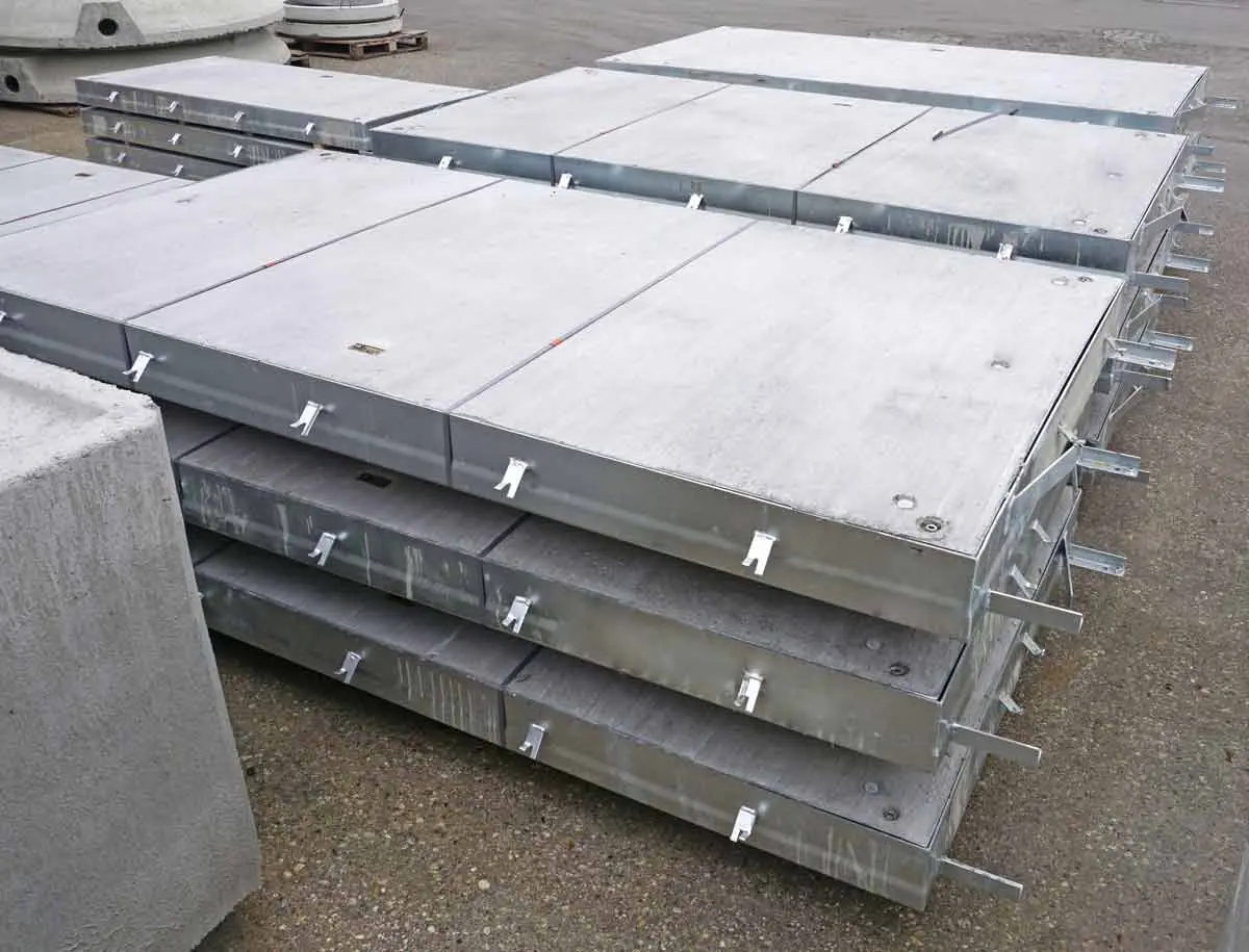 Stapeln von Beton-Schachtabdeckungen mit Metallgriffen auf einer Oberfläche.