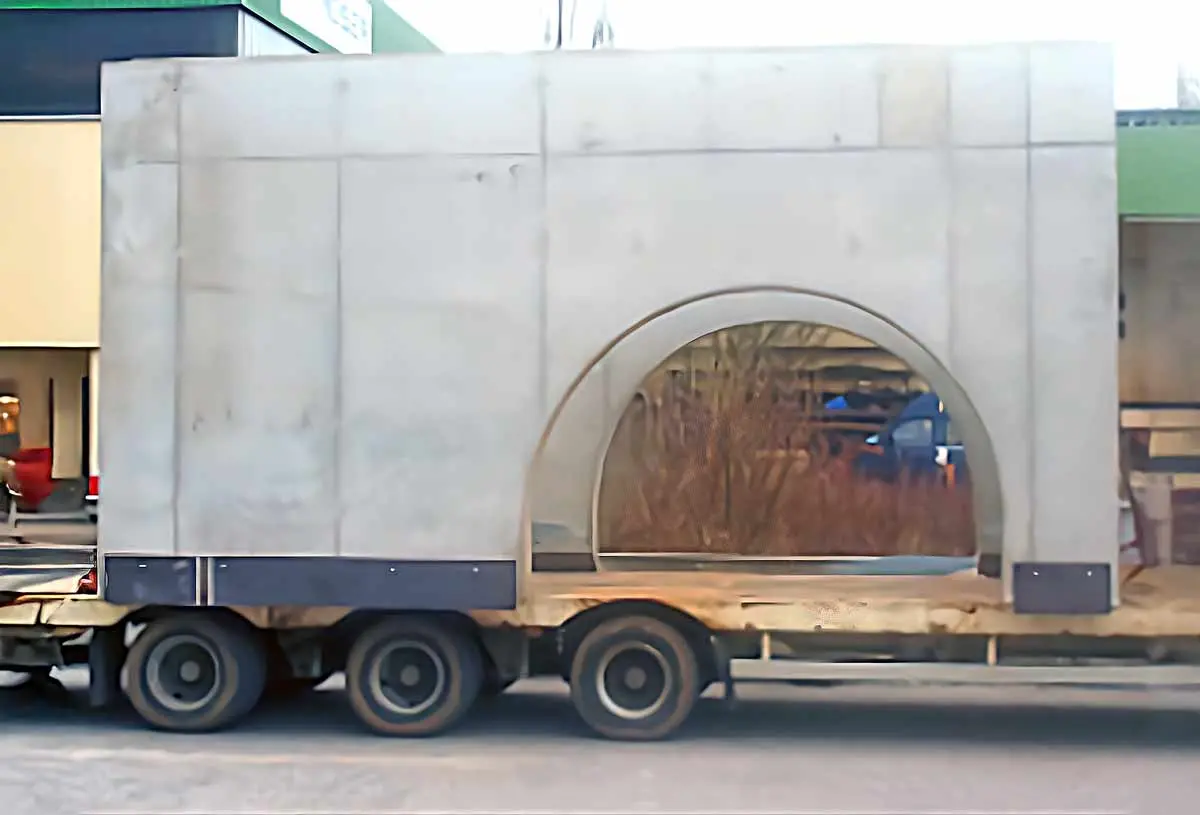 Ein Betonmodul mit einem großen, runden Fenster auf einem Anhänger.