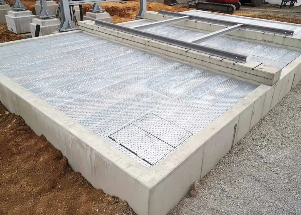 Betonplatte mit einem Gitterrost auf der Oberfläche, teilweise montiert auf einer Baustelle.