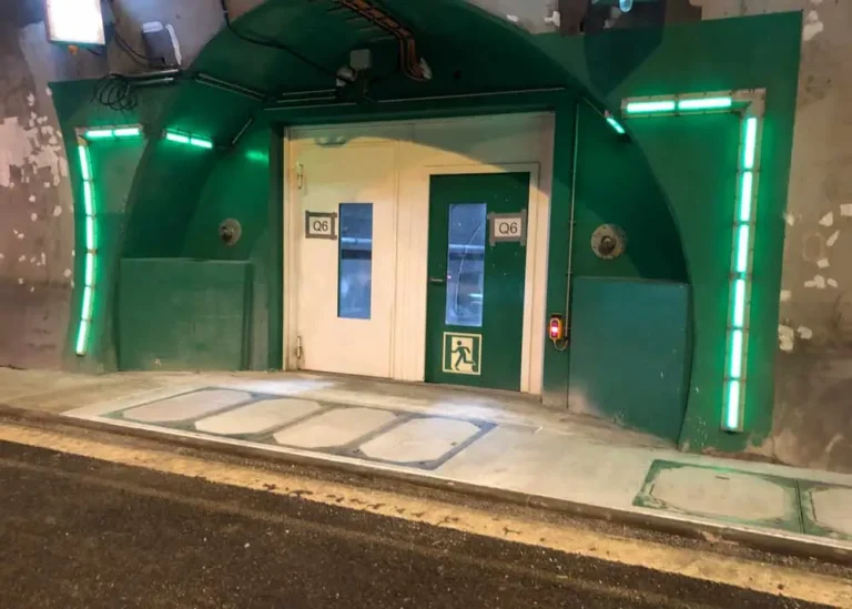 Grüner Tunnel mit einer Tür und Notausgangssymbol, beleuchtet von grünen Lichtern.