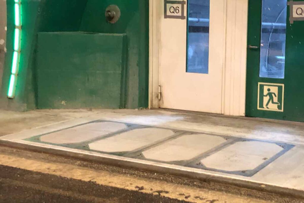 Betonabdeckung für einen Tunnelschacht mit grünen Wänden und Türen im Hintergrund.
